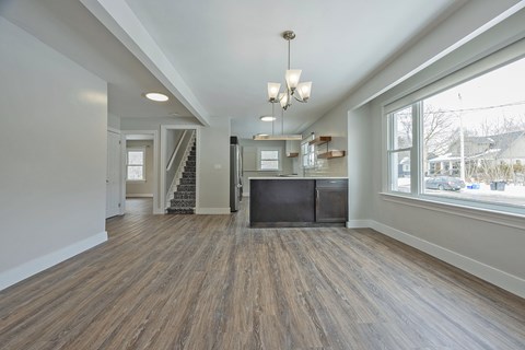 A spacious room with wooden floors and a staircase.