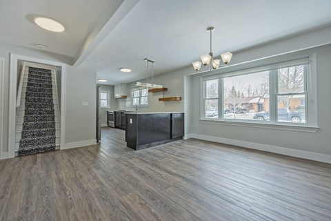 A spacious room with wood flooring and a large window.