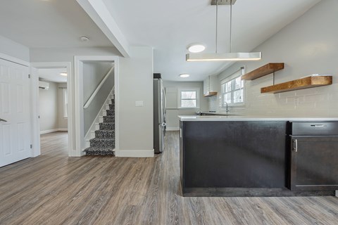 A kitchen with a black countertop and a staircase in the background.