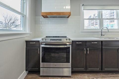 A modern kitchen with a stainless steel oven and black cabinets.