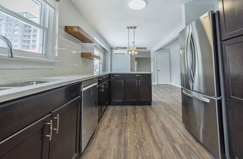 A modern kitchen with dark wood floors and stainless steel appliances.