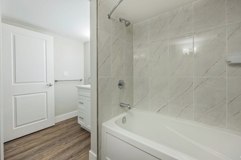 A white bathroom with a marble tile shower.