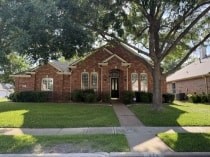 A brick house with a tree in front.