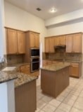 A kitchen with brown cabinets and a granite counter top.