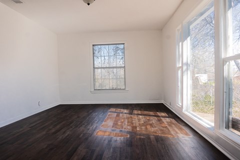 A room with a window and a wooden floor.