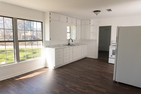 A kitchen with white cabinets and a wooden floor.