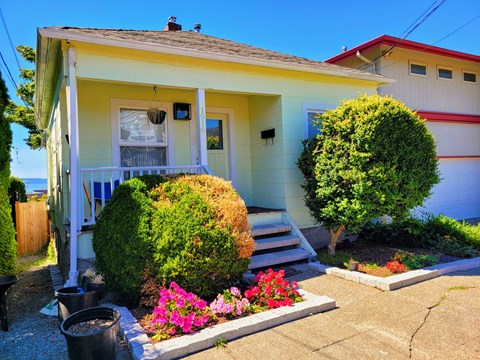 A yellow house with a red roof and a white fence.