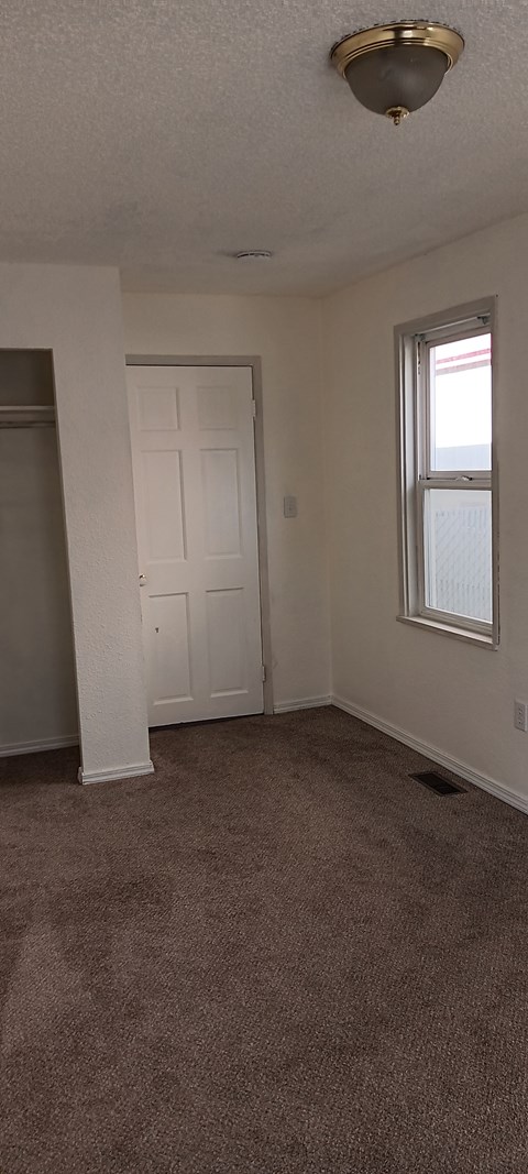A room with a carpeted floor and a white door.