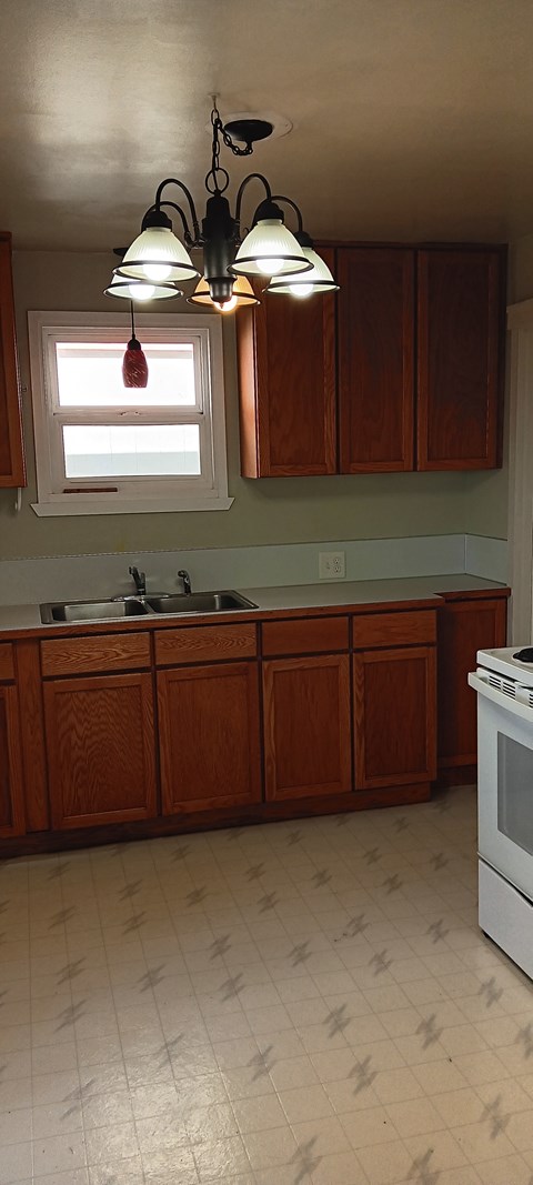 A kitchen with wooden cabinets and a white stove.