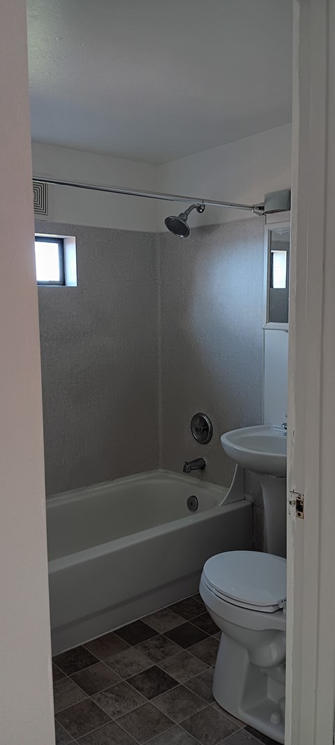 A white toilet sits next to a bathtub in a bathroom.