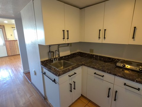 A kitchen with white cabinets and a granite countertop.