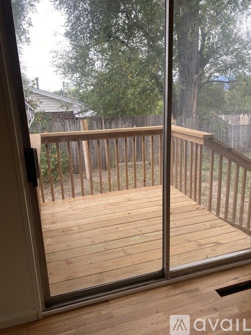 A wooden deck with a glass door leading to a backyard.