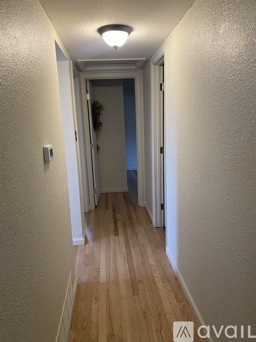 A long hallway with wood floors and white walls.