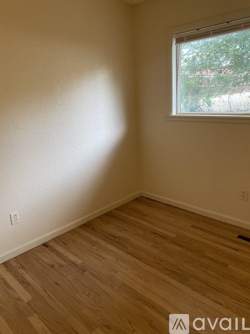 A room with wooden flooring and a window.