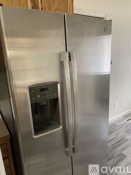 A stainless steel refrigerator with the door open and a water dispenser in the middle.