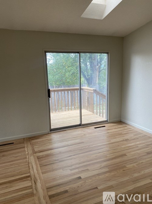 A room with wooden flooring and a sliding glass door leading to a deck.