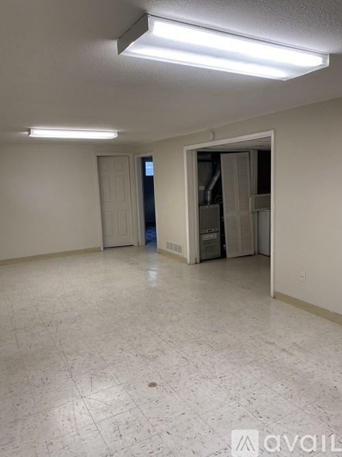 A room with white walls and a tiled floor with a door on the left and an open door on the right.