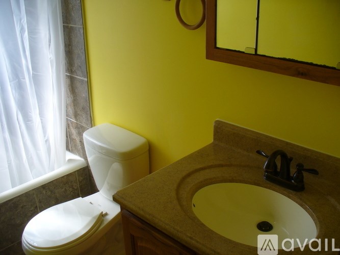 A bathroom with a toilet, sink and mirror.