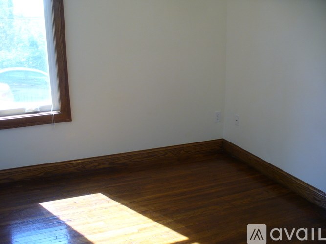 A room with wooden floors and a window letting in sunlight.