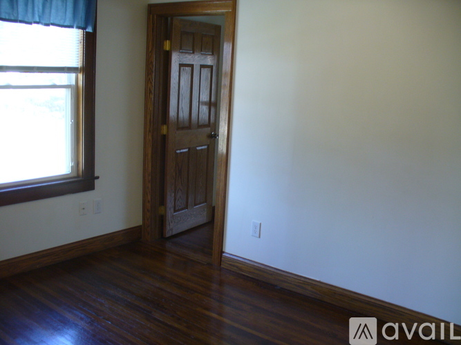 A room with a wooden door and a window with a blue curtain.