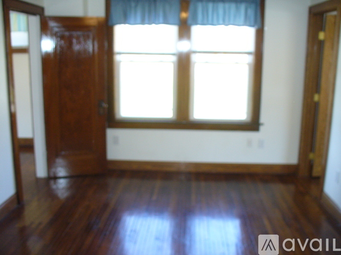 A room with a wooden floor and a window with a blue curtain.