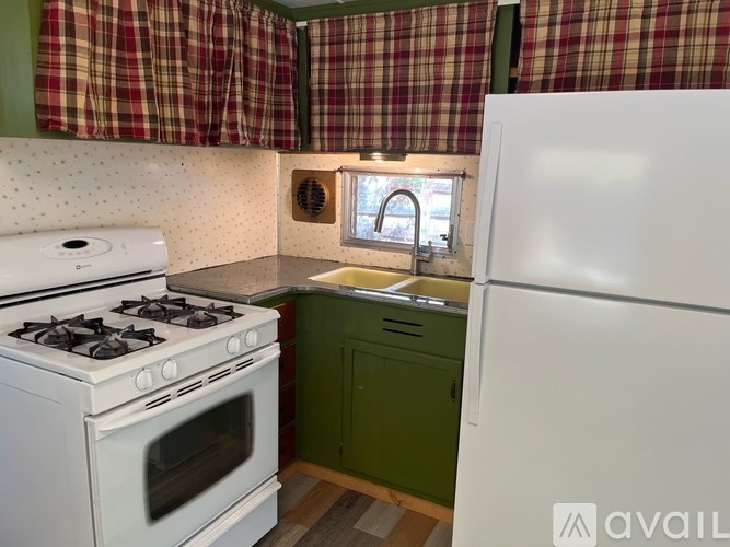 A kitchen with a white stove and green cabinets.