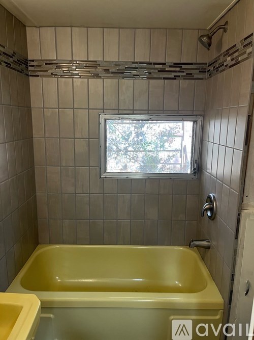 A bathroom with a yellow tub and a window.