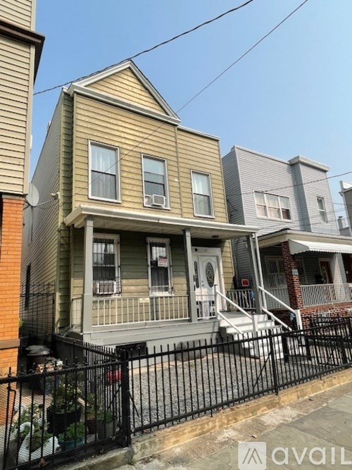 A two-story house with a front porch and a black fence.
