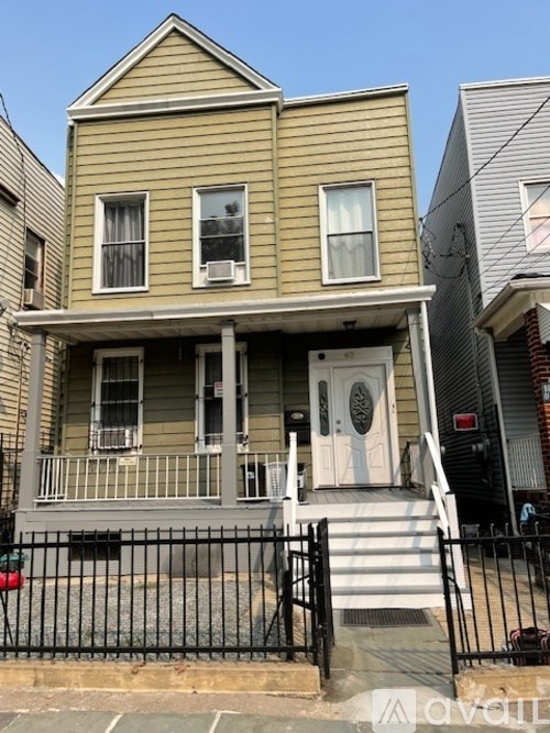 A two-story house with a front porch and a black fence.