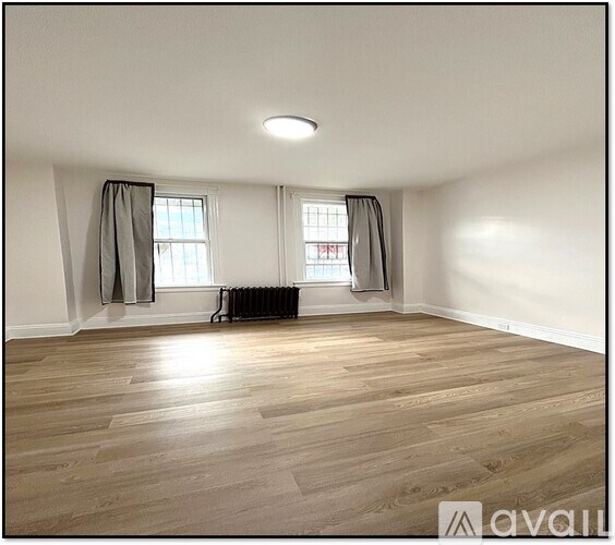 A room with wooden flooring and a window with curtains.