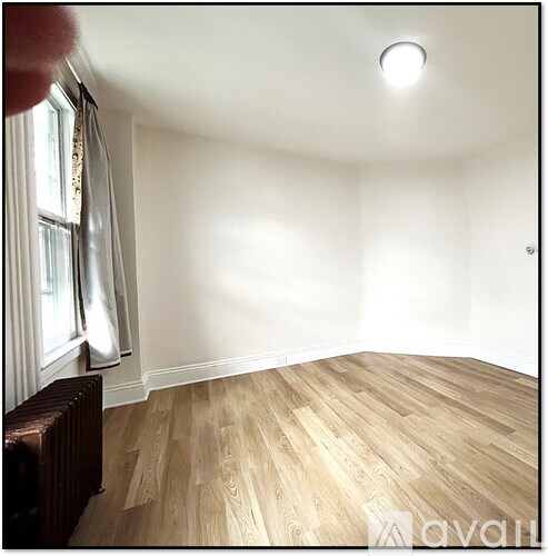 A room with wooden flooring and a radiator to the left.