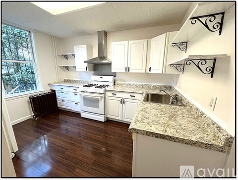 A kitchen with white cabinets and a granite countertop.