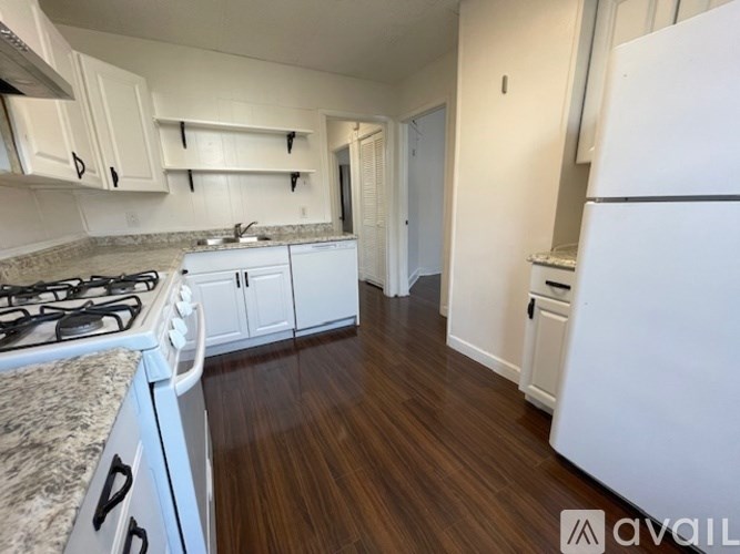 A kitchen with white appliances and wooden floors.