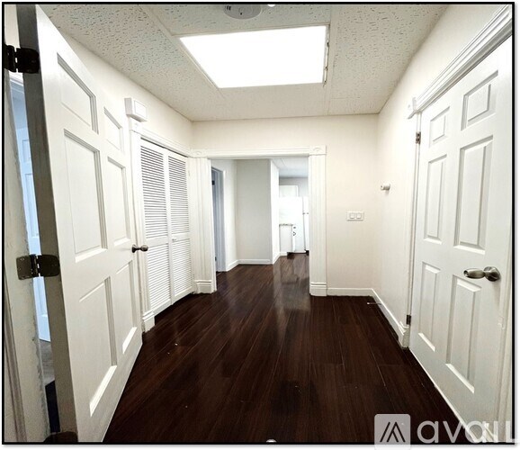 A hallway with white doors and wooden floors.