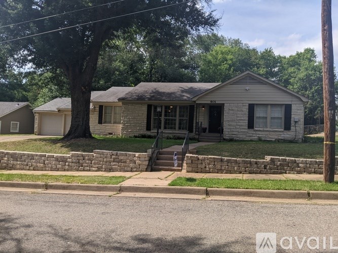A house with a stone wall and a tree in front.