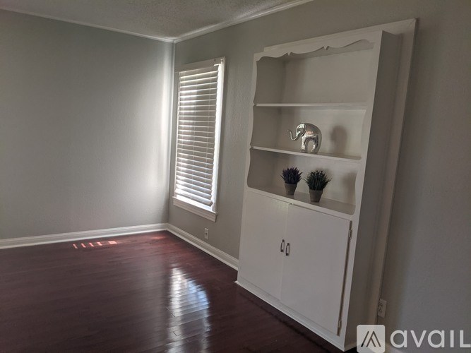 A room with a white cabinet and a window with blinds.