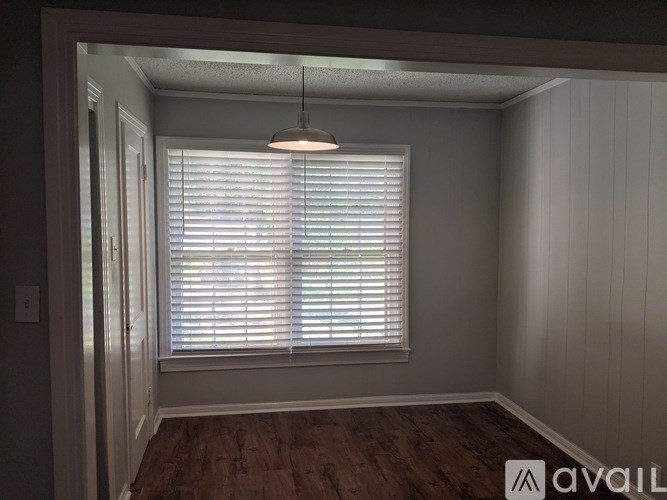 A room with a window covered in blinds and a light hanging from the ceiling.