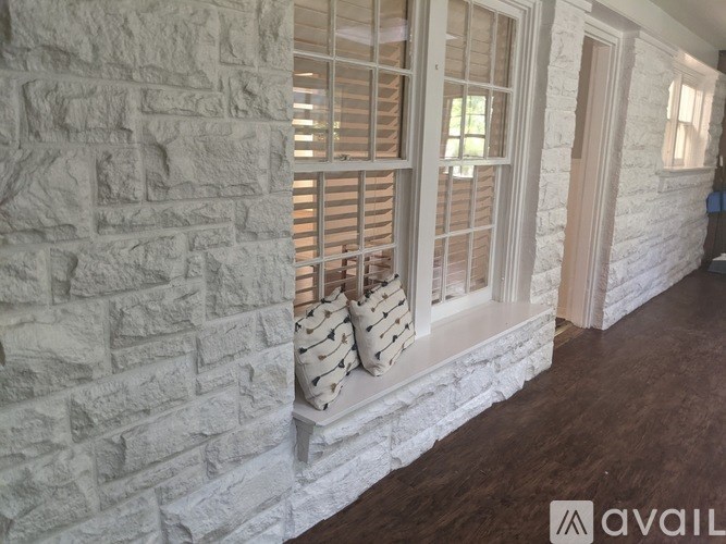 A room with a white brick wall and a window with wooden blinds.