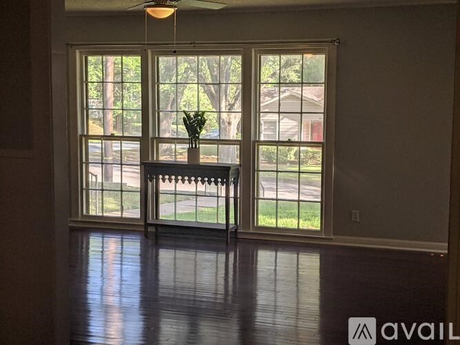 A room with a large window and a vase on the window sill.