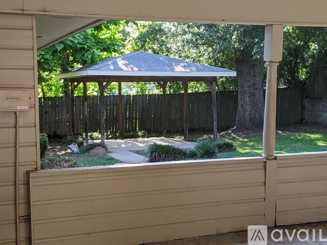 A gazebo is in the middle of a yard.