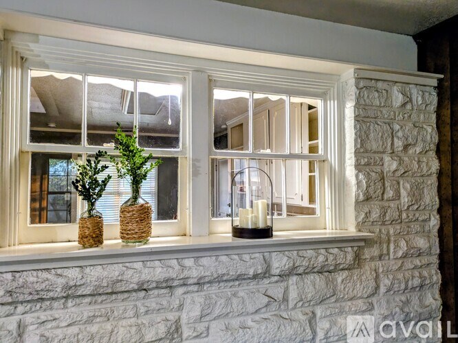 A white stone wall with a window and a candle on the windowsill.
