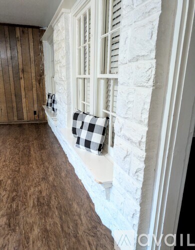 A window with a black and white checkered pillow is on a white stone wall.
