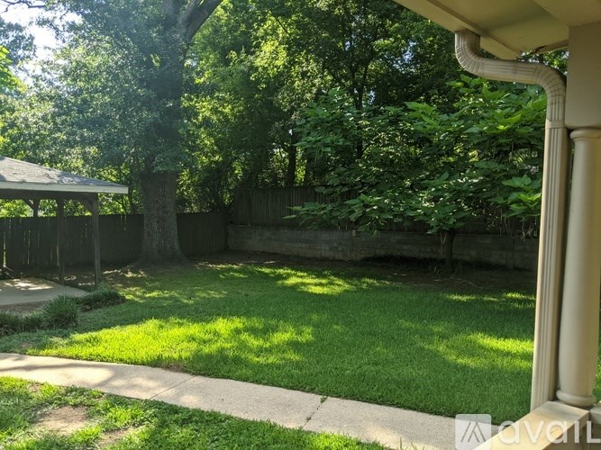 A backyard with a well-maintained lawn and a gazebo.