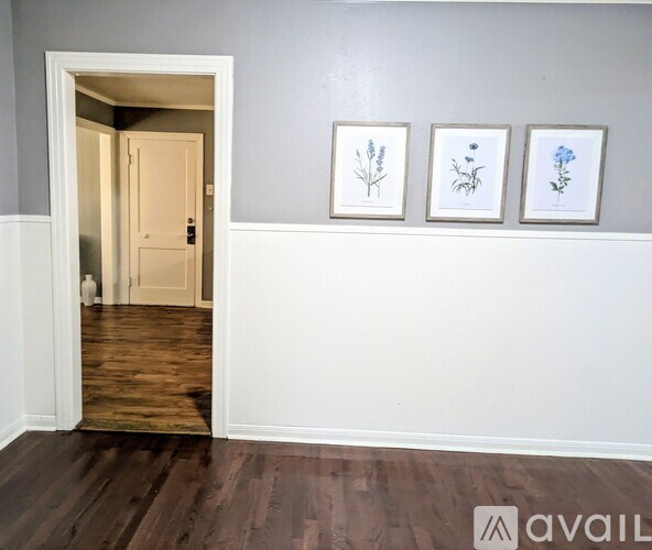 A hallway with a doorway leading to another room, and three framed botanical prints on the wall.