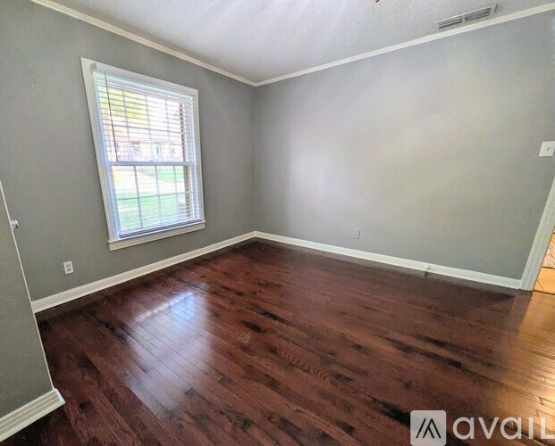 A room with wooden flooring and a window.