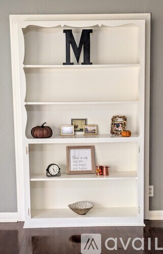 A white shelf with decorative items and a letter M on the top.