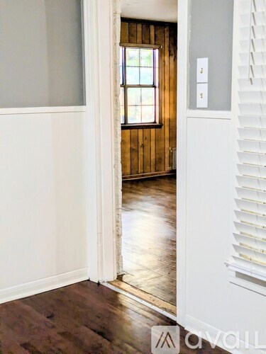 A room with a white door and a window with wooden panels on the wall.