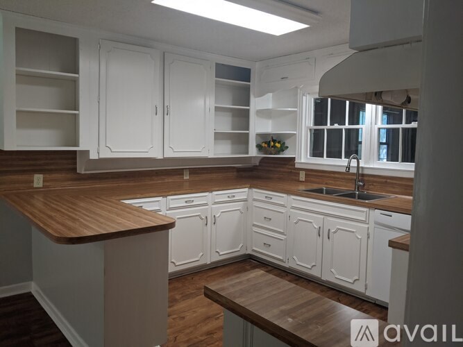 A kitchen with white cabinets and a wooden countertop.