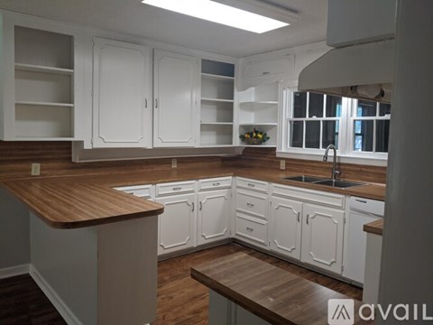A kitchen with white cabinets and a wooden countertop.