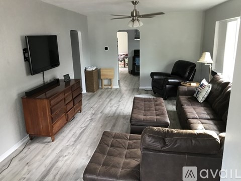 A living room with a brown leather couch and a wooden cabinet.